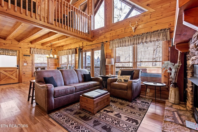 living room with wood walls, hardwood / wood-style flooring, a notable chandelier, wood ceiling, and beam ceiling