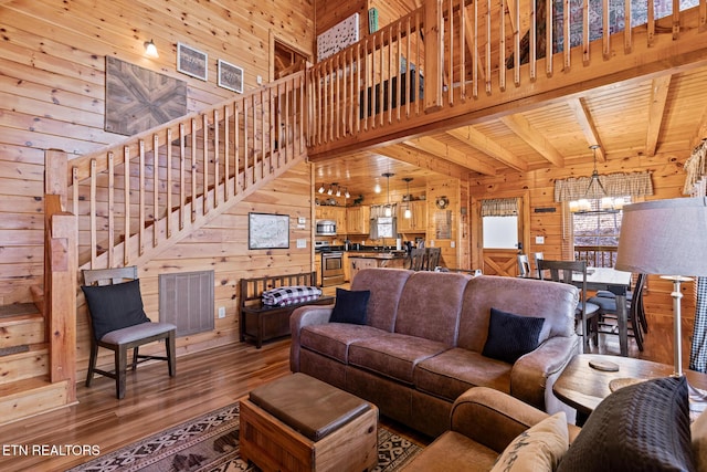 living room featuring wood walls, a chandelier, a healthy amount of sunlight, wooden ceiling, and beam ceiling