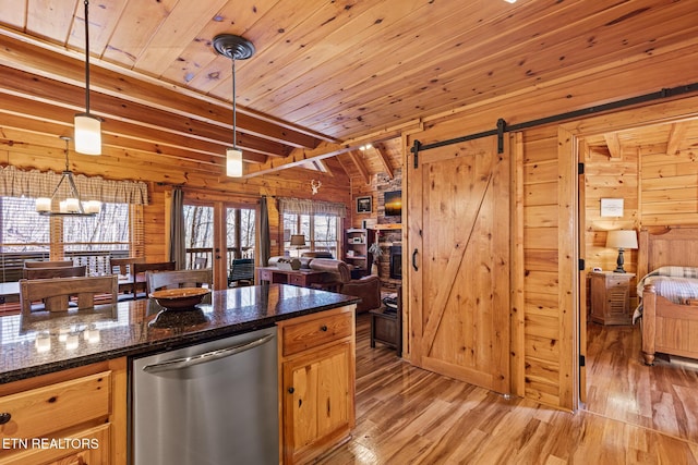 kitchen featuring hanging light fixtures, wooden ceiling, stainless steel dishwasher, a barn door, and wood walls