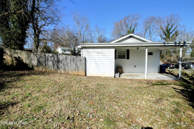 view of side of property featuring a carport, a patio area, and a lawn