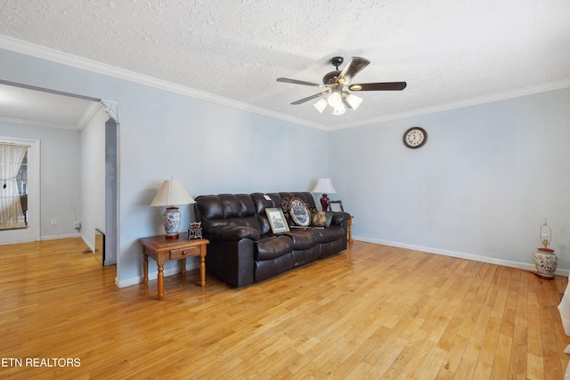 living room with crown molding, ceiling fan, a textured ceiling, and light hardwood / wood-style floors