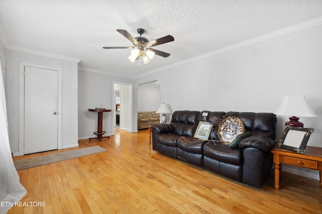 living room featuring crown molding, ceiling fan, a textured ceiling, and light wood-type flooring