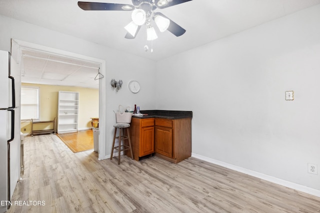 bar featuring ceiling fan, white fridge, and light wood-type flooring