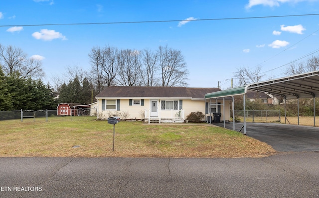 ranch-style home featuring a carport, a front lawn, and a storage shed