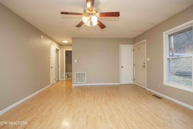 empty room with ceiling fan and light hardwood / wood-style floors