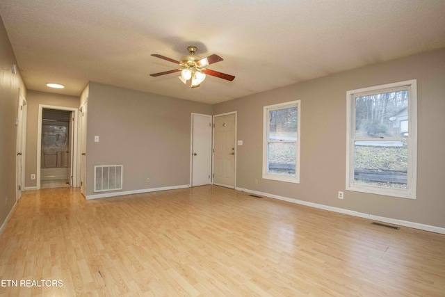 unfurnished room with ceiling fan, a textured ceiling, and light wood-type flooring