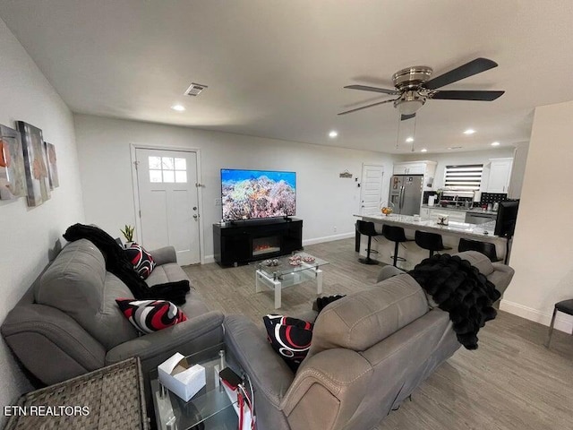 living room featuring ceiling fan and light hardwood / wood-style floors