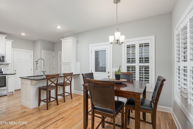 dining area featuring sink, an inviting chandelier, and light wood-type flooring