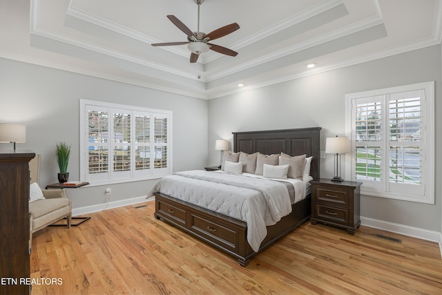 bedroom featuring ceiling fan, ornamental molding, a raised ceiling, and multiple windows