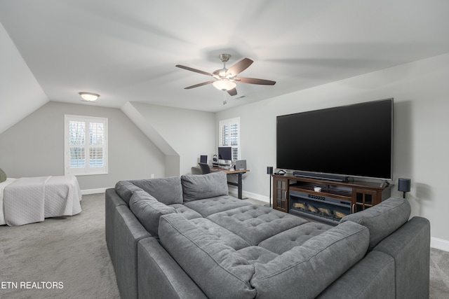 carpeted living room with ceiling fan, vaulted ceiling, and plenty of natural light