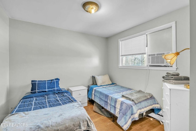 bedroom with cooling unit and light hardwood / wood-style flooring