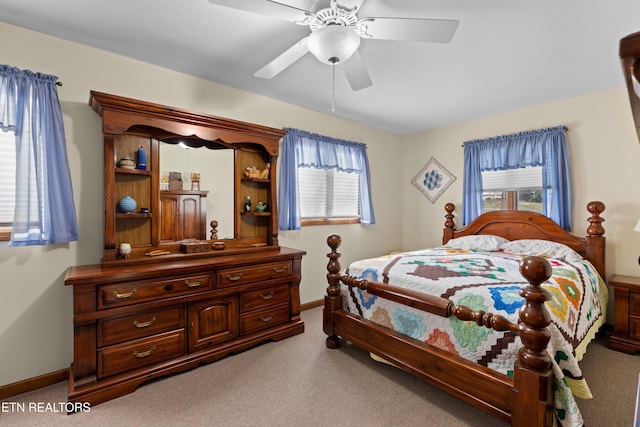 bedroom featuring ceiling fan, multiple windows, and light carpet