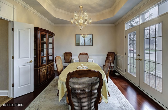 dining area featuring a raised ceiling, a chandelier, dark hardwood / wood-style flooring, and french doors