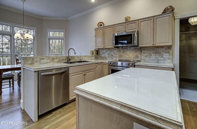 kitchen with sink, a center island, hanging light fixtures, appliances with stainless steel finishes, and decorative backsplash