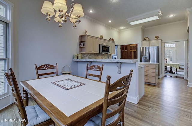 dining area with crown molding, a chandelier, and light hardwood / wood-style flooring