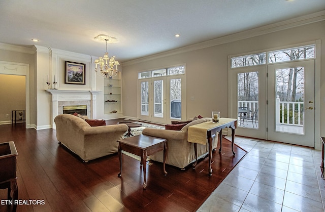 living room featuring french doors, ornamental molding, a tiled fireplace, and a wealth of natural light