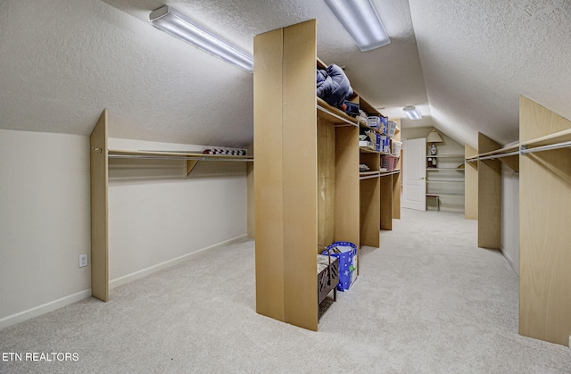 walk in closet with vaulted ceiling and light carpet