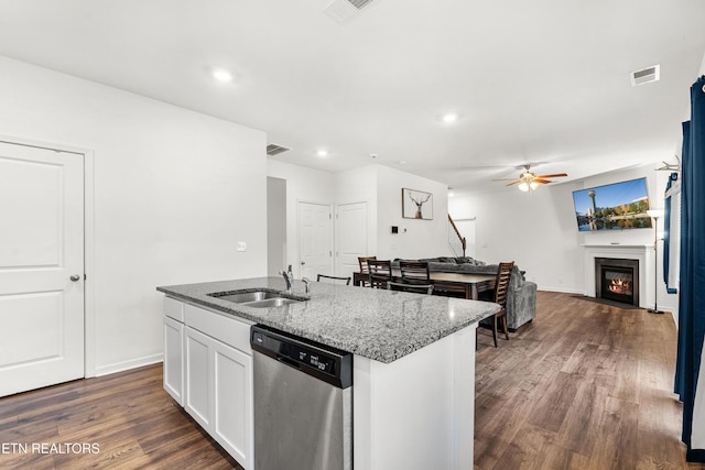 kitchen featuring white cabinetry, stainless steel dishwasher, sink, light stone counters, and a center island with sink