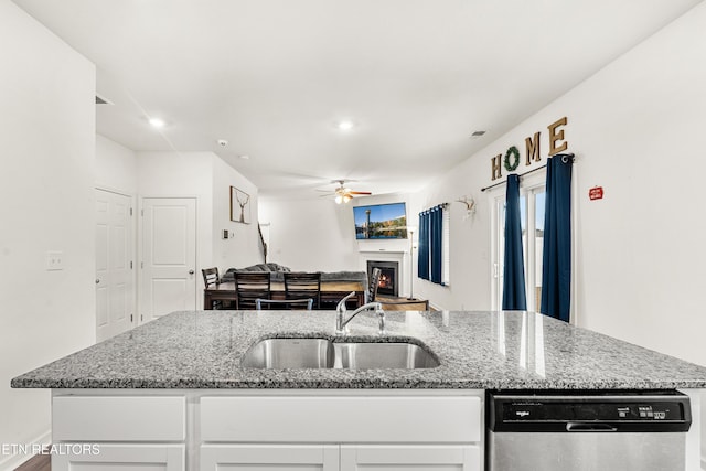 kitchen with sink, white cabinetry, light stone counters, and stainless steel dishwasher