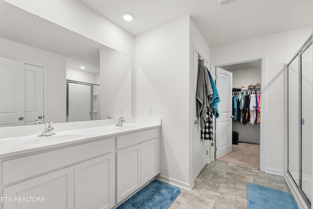 bathroom featuring a shower with door and vanity