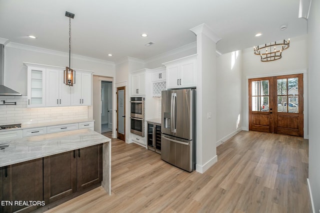 kitchen with white cabinetry, ornamental molding, backsplash, stainless steel appliances, and light stone counters