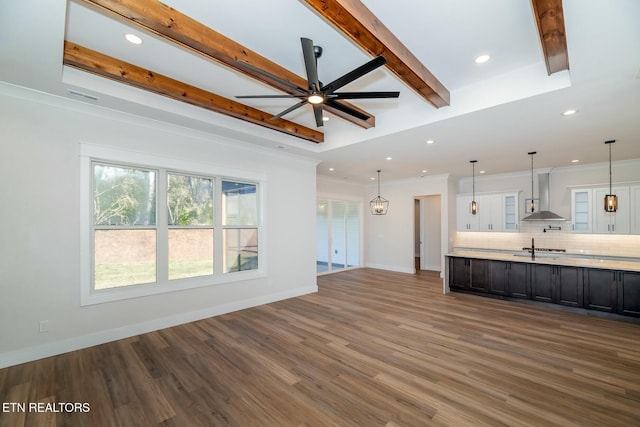 unfurnished living room featuring ceiling fan, dark wood-type flooring, a raised ceiling, and crown molding