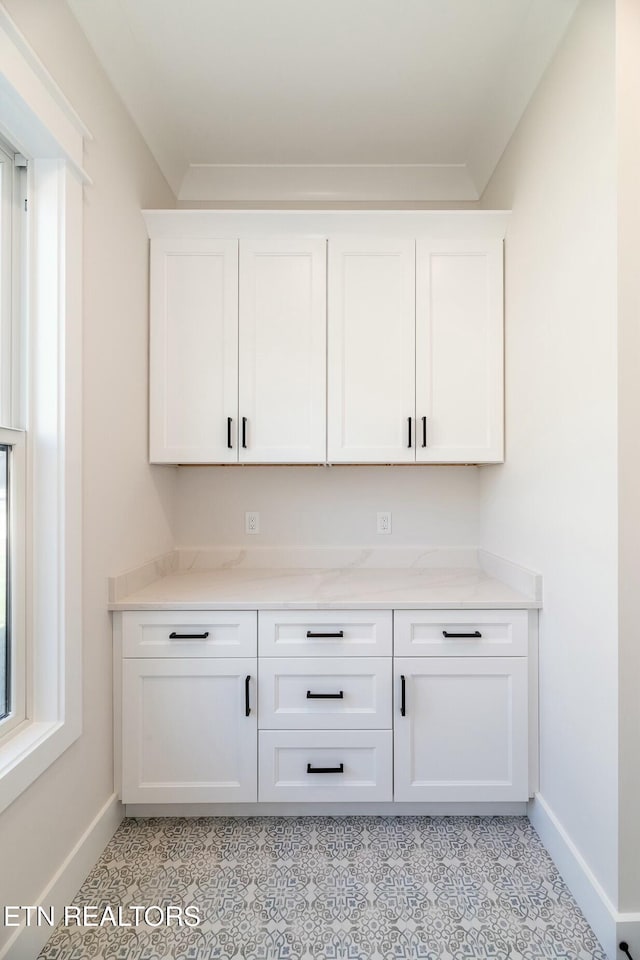 bar with white cabinets and light stone countertops