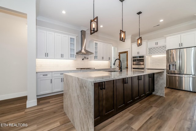 kitchen featuring a large island, wall chimney exhaust hood, sink, white cabinets, and appliances with stainless steel finishes