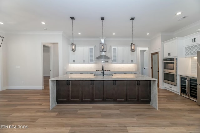 kitchen featuring decorative light fixtures, white cabinets, double oven, and a spacious island