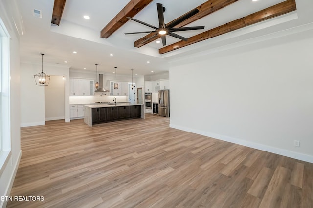 unfurnished living room featuring sink, light wood-type flooring, and ceiling fan with notable chandelier