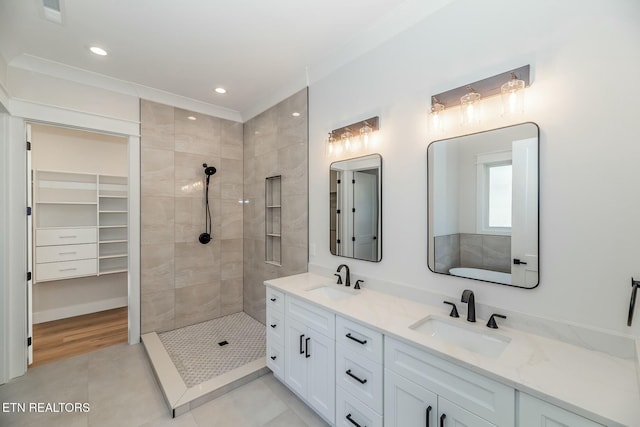 bathroom featuring vanity, tiled shower, ornamental molding, and tile patterned flooring