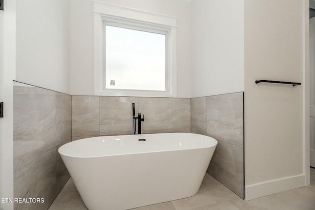 bathroom with a washtub and tile walls