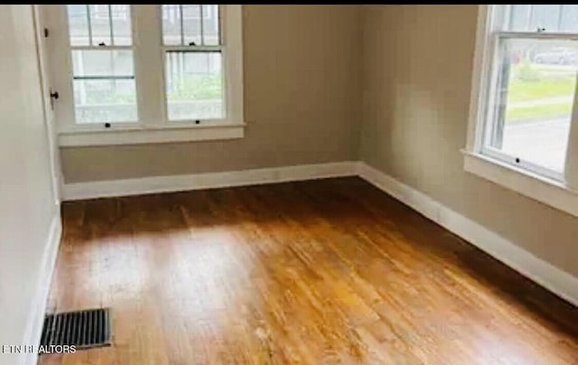 spare room with hardwood / wood-style floors and a wealth of natural light