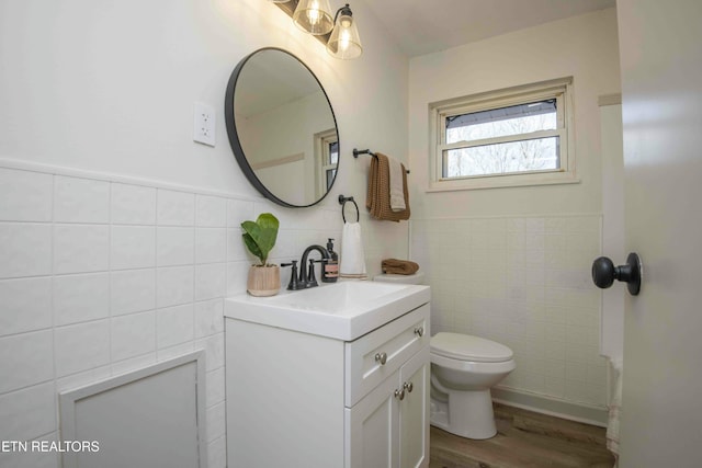 bathroom featuring hardwood / wood-style flooring, vanity, tile walls, and toilet