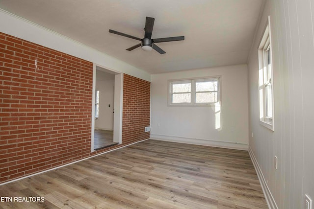 unfurnished bedroom featuring brick wall, ceiling fan, and light hardwood / wood-style floors