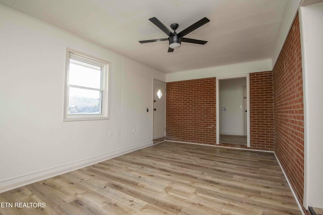 spare room featuring ornamental molding, brick wall, ceiling fan, and light hardwood / wood-style flooring