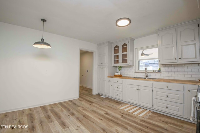 kitchen with pendant lighting, white cabinetry, wooden counters, and sink