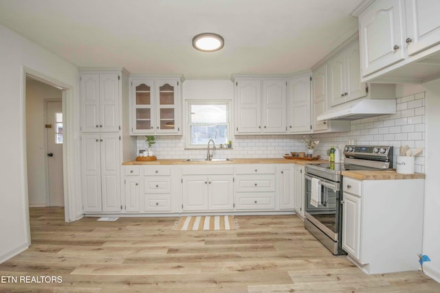 kitchen with stainless steel electric stove, sink, white cabinets, and wood counters