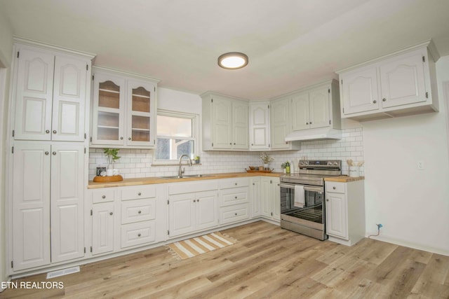 kitchen featuring stainless steel electric range, sink, wooden counters, white cabinets, and light hardwood / wood-style flooring