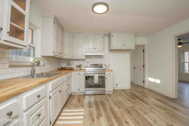 kitchen featuring stainless steel range with electric stovetop, wooden counters, sink, and white cabinets