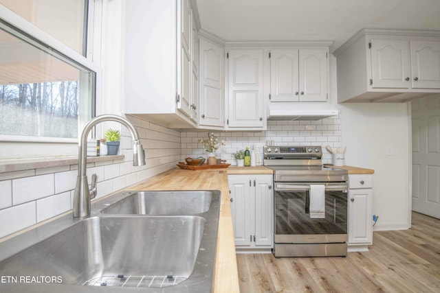 kitchen with electric stove, white cabinetry, butcher block counters, and sink