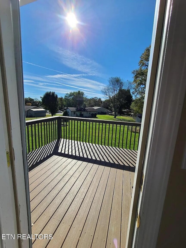 wooden deck featuring a lawn