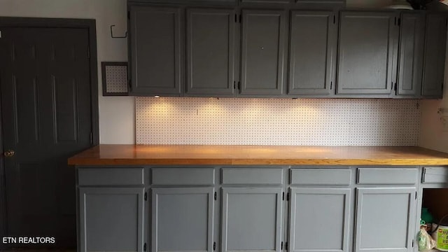 kitchen featuring backsplash, gray cabinetry, and wooden counters