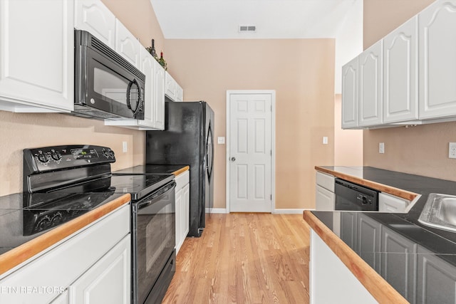 kitchen featuring black appliances, light wood-type flooring, and white cabinetry