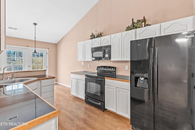 kitchen featuring light hardwood / wood-style flooring, decorative light fixtures, sink, white cabinetry, and black appliances