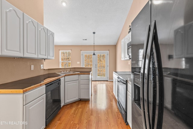 kitchen featuring black appliances, white cabinetry, pendant lighting, and sink