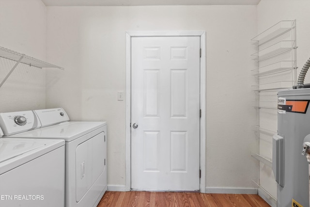 clothes washing area featuring washer and clothes dryer, light hardwood / wood-style floors, and electric water heater