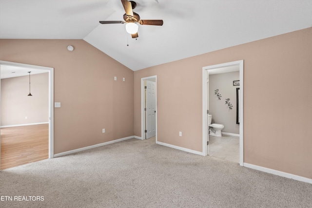 unfurnished bedroom with ceiling fan, light colored carpet, connected bathroom, and vaulted ceiling