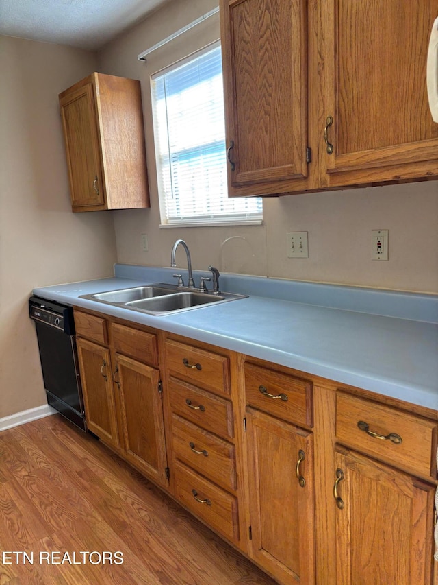 kitchen with light hardwood / wood-style floors, black dishwasher, and sink