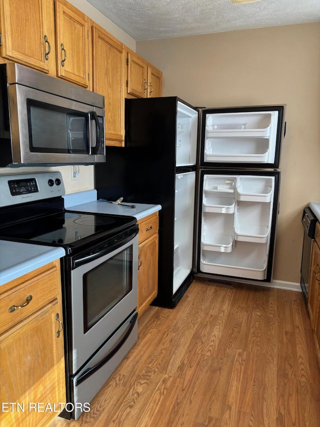 kitchen with stainless steel appliances, light hardwood / wood-style floors, and a textured ceiling